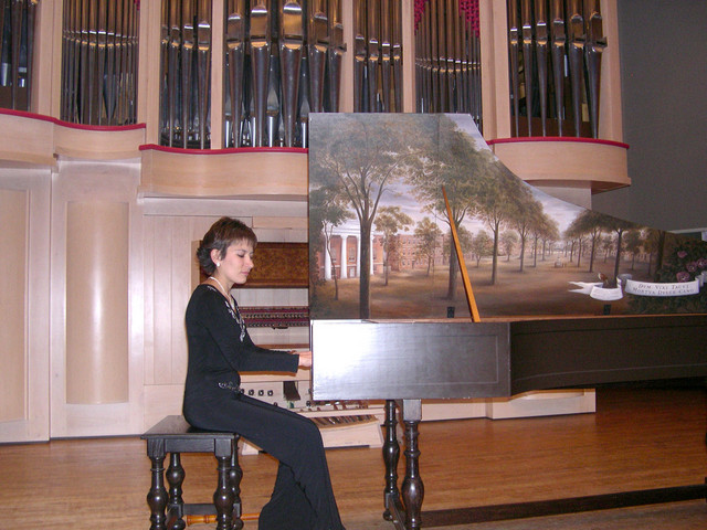 Alejandra with the harpsichord at the University of S.Carolina. Painting is of the early days of the university. 